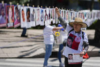 A woman hangs a portrait of a missing person on a makeshift line along Reforma Avenue during a march demanding the government do more to locate their loved ones, marking International Day of the Disappeared, in Mexico City, Wednesday, Aug. 30, 2023. Mothers of some of 111,000 people who have disappeared in Mexico over decades of violence, most believed to have been abducted by drug cartels or kidnapped by gangs, gathered Wednesday, on Mexico City's iconic boulevard. (AP Photo/Eduardo Verdugo)
