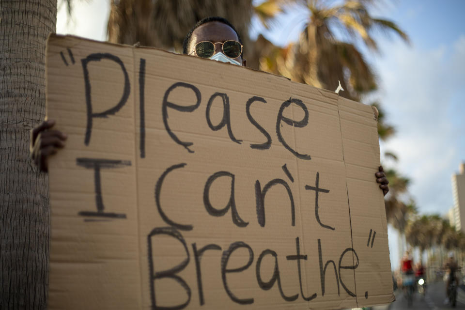 A protester holds a sign during a protest to decry the killing of George Floyd in front of the American embassy in Tel Aviv, Israel, Tuesday, June 2, 2020.(AP Photo/Ariel Schalit)