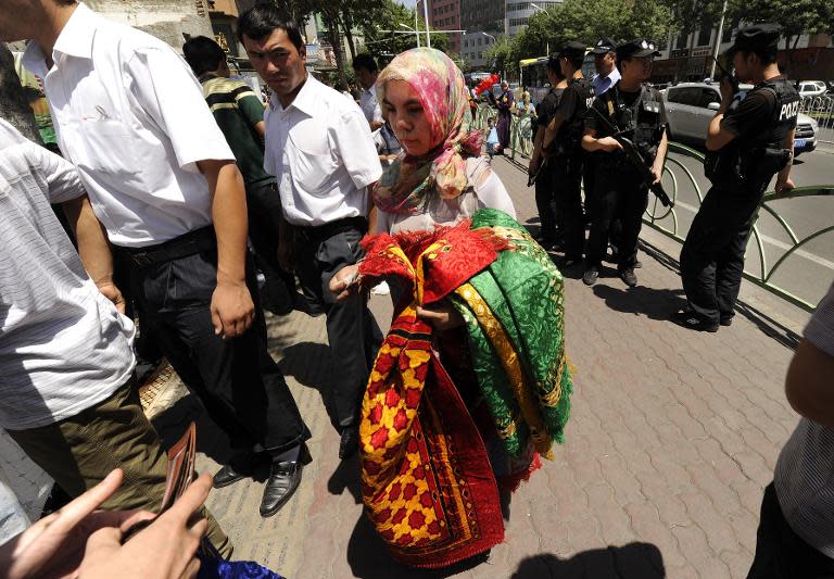 Armed police (R) keep watch as Muslim ethnic Uighurs gather before Friday prayers outside a Mosque in Urumqi, capital of China's Xinjiang region in 2010