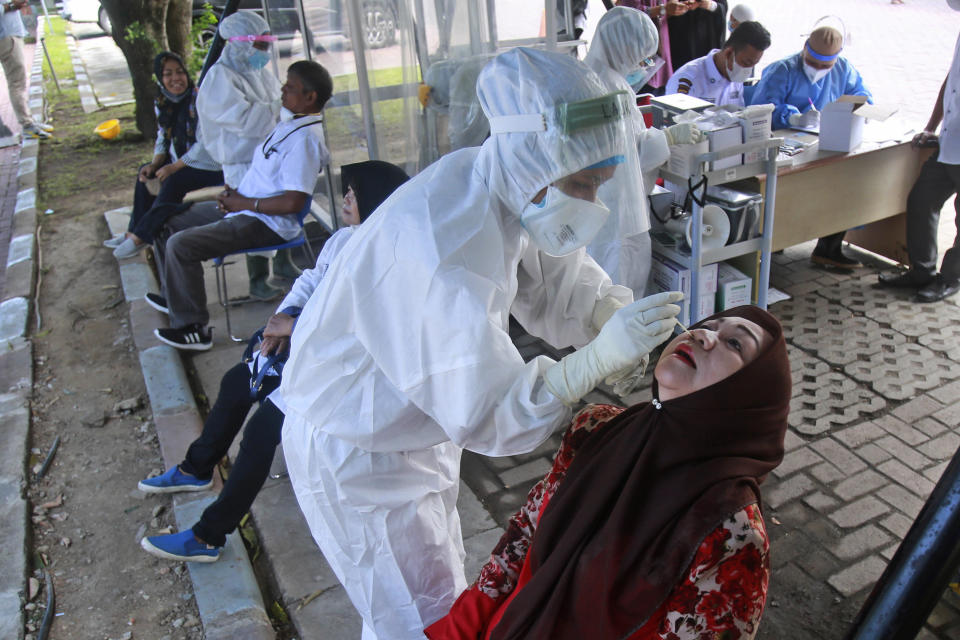 A medical workers collect nasal swab samples from a woman to be tested for coronavirus during a COVID-19 screening at University of North Sumatra in Medan, Indonesia, Monday, June 21, 2021. Indonesia has reported more coronavirus cases than any other country in Southeast Asia. (AP Photo/Binsar Bakkara)