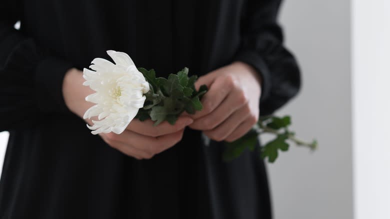 Person in black holding white flower