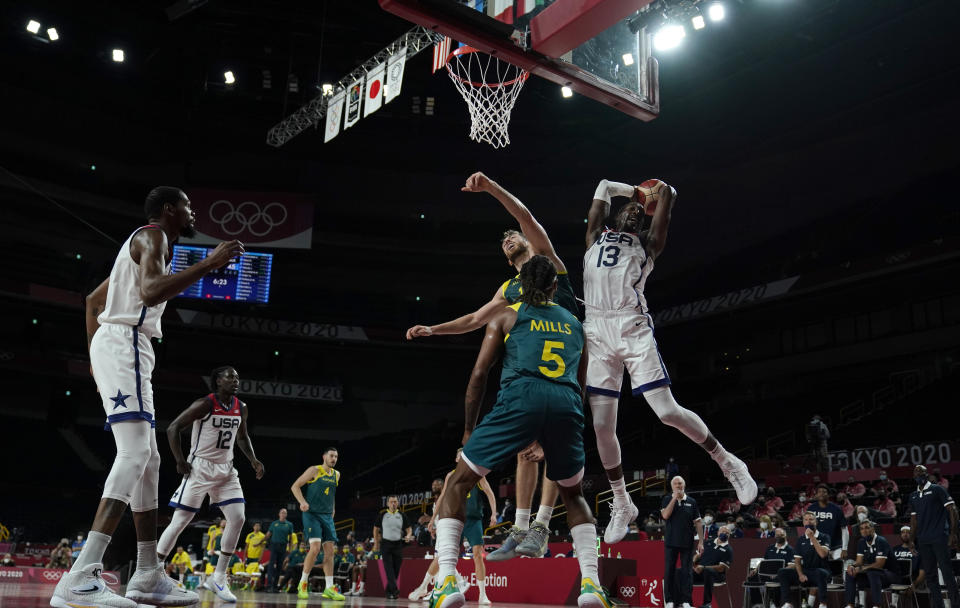 United States's Bam Adebayo (13) grabs a rebound over Australia's Patty Mills (5) and Nic Kay (15) during men's basketball semifinal game at the 2020 Summer Olympics, Thursday, Aug. 5, 2021, in Saitama, Japan. (AP Photo/Charlie Neibergall)