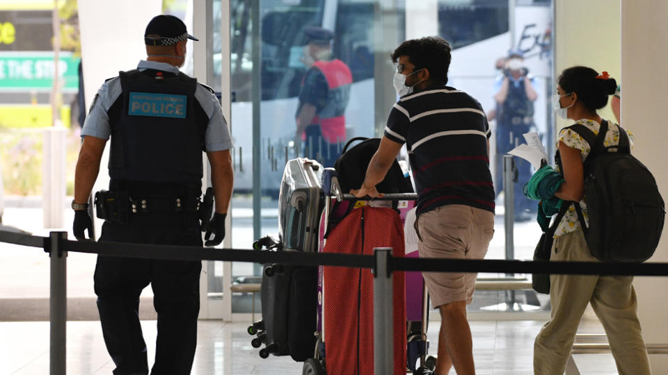 Travellers inside Adelaide Airport wear face masks as they are escorted into quarantine.