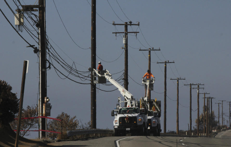 FILE- In this Nov. 25, 2018 file photo utility crews repair overhead lines Sunday, , along Pacific Coast Highway just west of Malibu, Calif., As California counties face the prospect of increased utility power shut-off meant to prevent wildfires, counties with more resources are adapting much more easily to the challenge than poorer ones. (AP Photo/John Antczak, File)