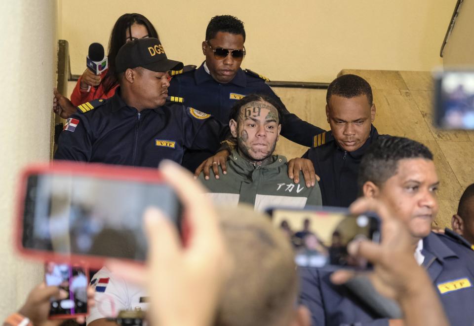 Rapper Daniel Hernandez, known as Tekashi 6ix9ine, is escorted by police as he arrives for a court hearing at the Palace of Justice, in Santo Domingo, Dominican Republic, Jan. 25, 2024. A judge conditionally released the U.S. rapper after he was arrested in the Dominican Republic on domestic violence charges. (AP Photo/Ricardo Hernandez)