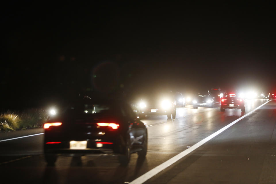 Car travel down Saddle Road near the Mauna Loa eruption, Tuesday, Nov. 29, 2022, near Hilo, Hawaii. Despite local authorities enforcing a no parking zone in the area near the eruption site, many spectators are flooding the area and illegally parking on the side of the highway. (AP Photo/Marco Garcia)