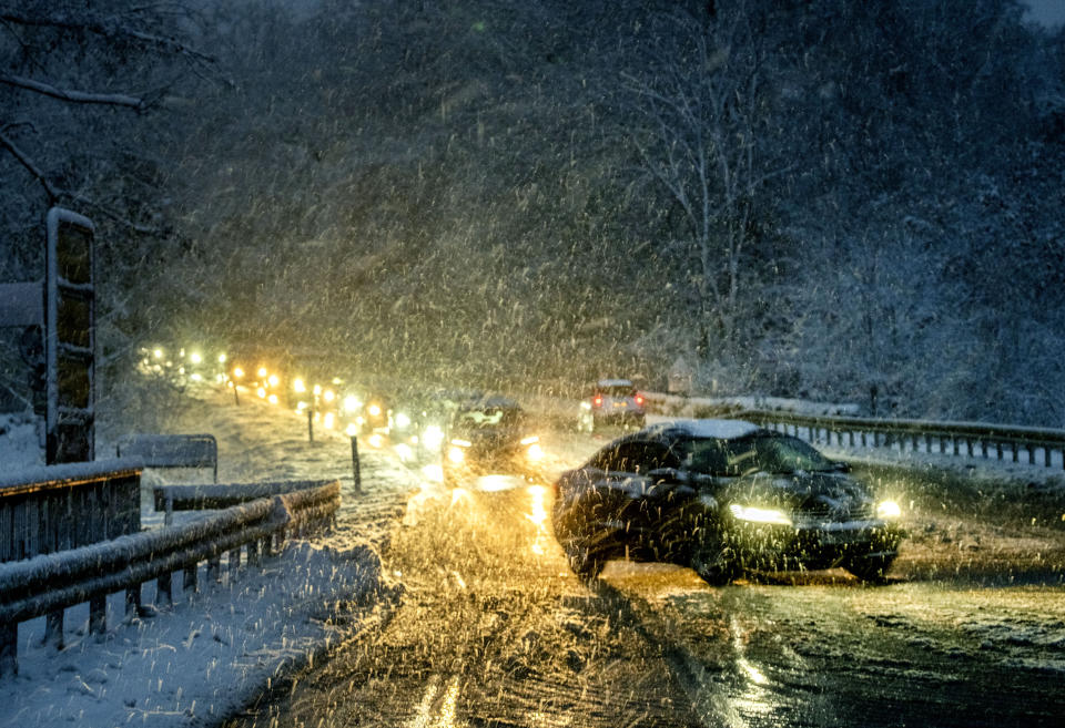 Commuters queue in heavy snowfalls on a country road in a forest of the Taunus region near Frankfurt, Germany, early Tuesday, Nov. 28, 2023. (AP Photo/Michael Probst)