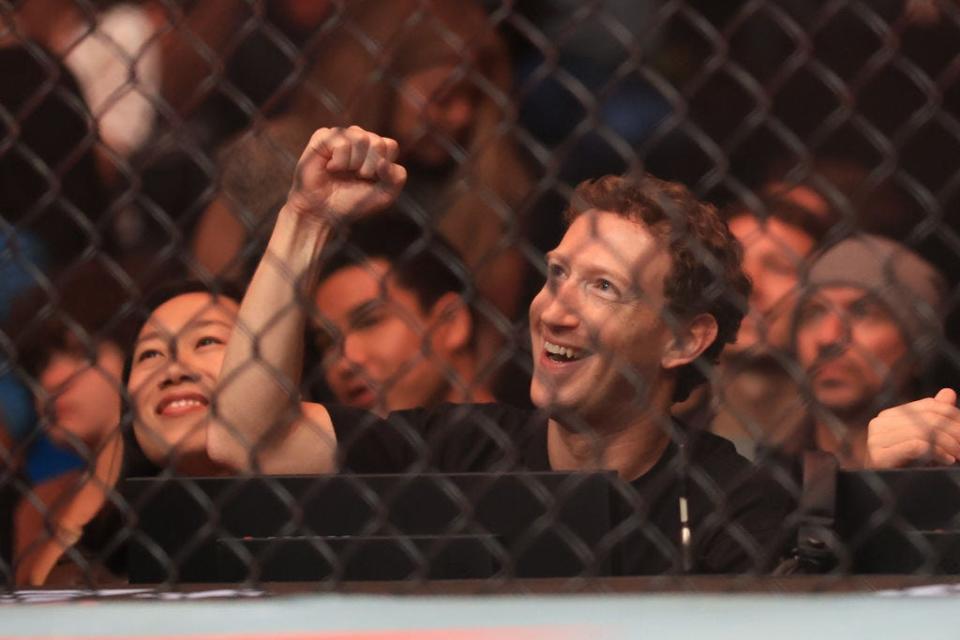 Mark Zuckerberg raises a fist cheering at a MMA match