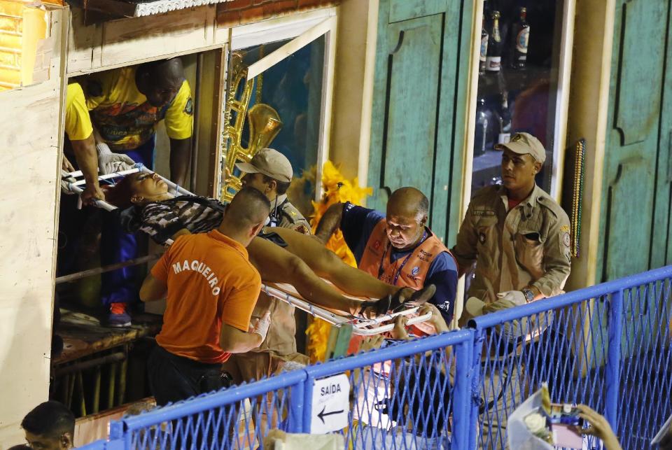 Firefighters carry an injured person on a stretcher to an ambulance during the performing of the Unidos da Tijuca samba school for the Carnival celebrations at the Sambadrome in Rio de Janeiro, Brazil, Tuesday, Feb. 28, 2017. Part of a float has collapsed during Rio de Janeiro's world famous Carnival parade, injuring several people, according to doctors at the scene. (AP Photo/Leo Correa)