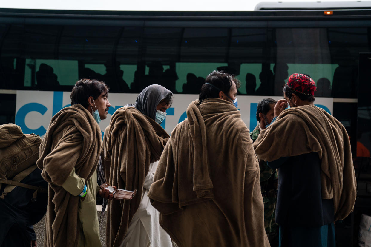 Evacuees who fled Afghanistan walk through the terminal to board buses that will take them to a processing center, at Dulles International Airport on Tuesday, Aug. 31, 2021. (Kent Nishimura / Los Angeles Times via Getty Images)
