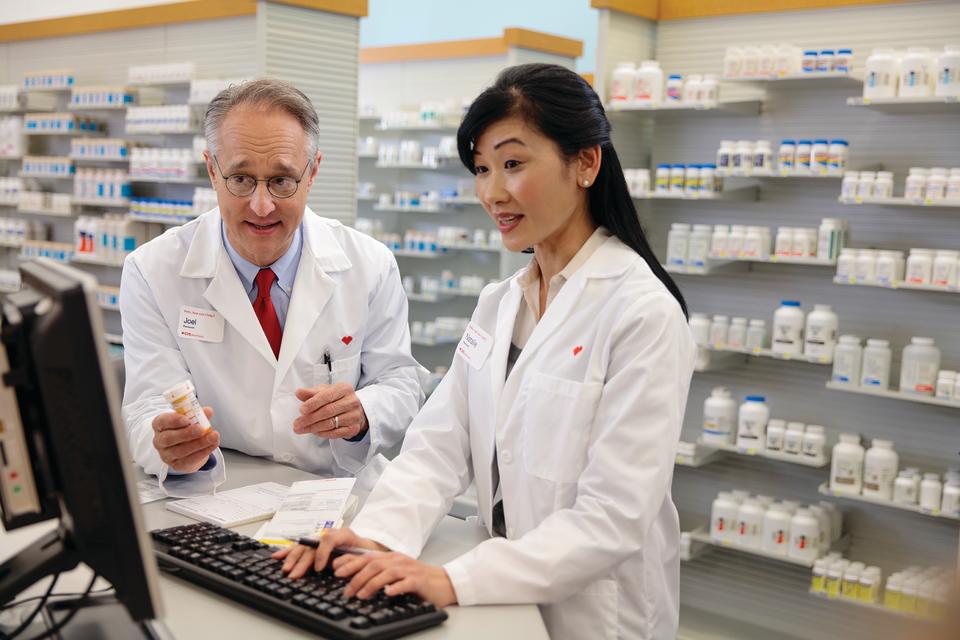 Two CVS pharmacists collaborating while using a computer.