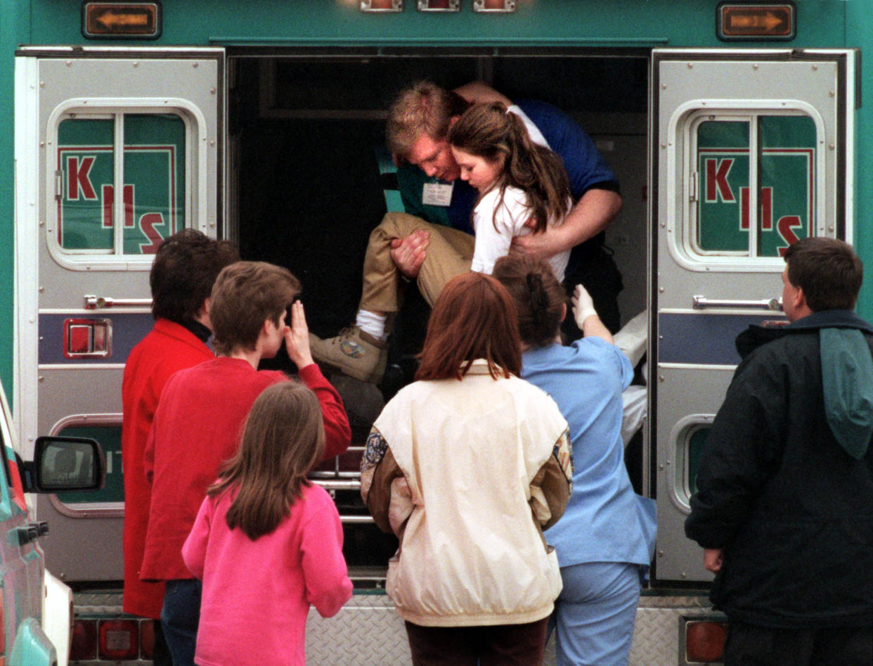 An emergency worker carries a young girl from an ambulance outside Westside Middle School, March 24, 1998