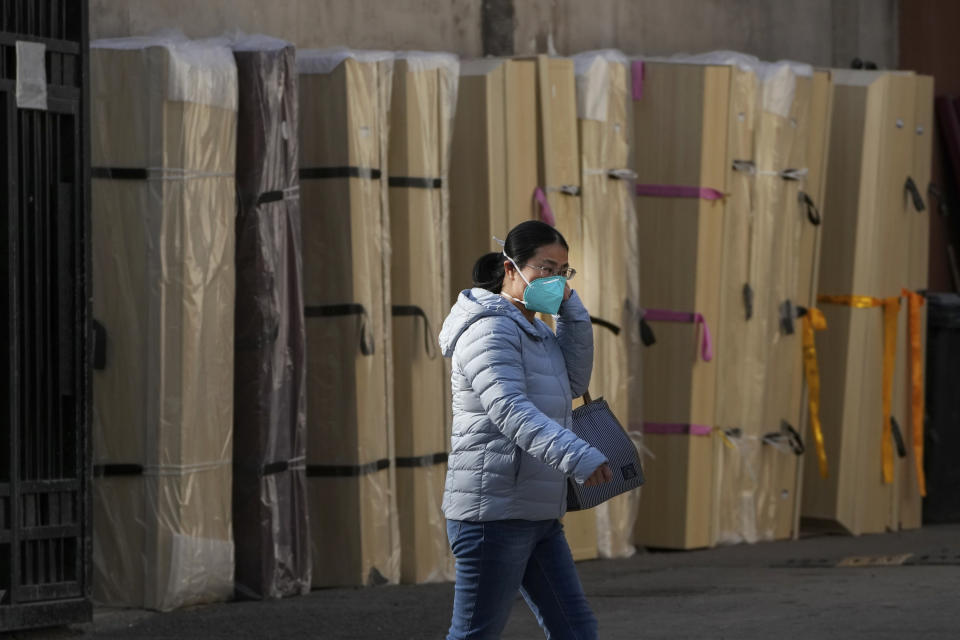 A woman wearing a face mask walks by empty coffins placed at a mortuary of a hospital in Beijing, Friday, Jan. 6, 2023. China is seeking to minimize the possibility of a major new COVID-19 outbreak during this month’s Lunar New Year travel rush following the end of most pandemic containment measures.(AP Photo/Andy Wong)