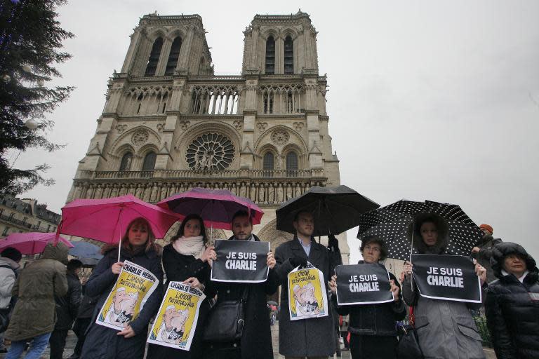 People hold signs reading "Je suis Charlie" as they mark a minute's silence in front of Notre-Dame Cathedral