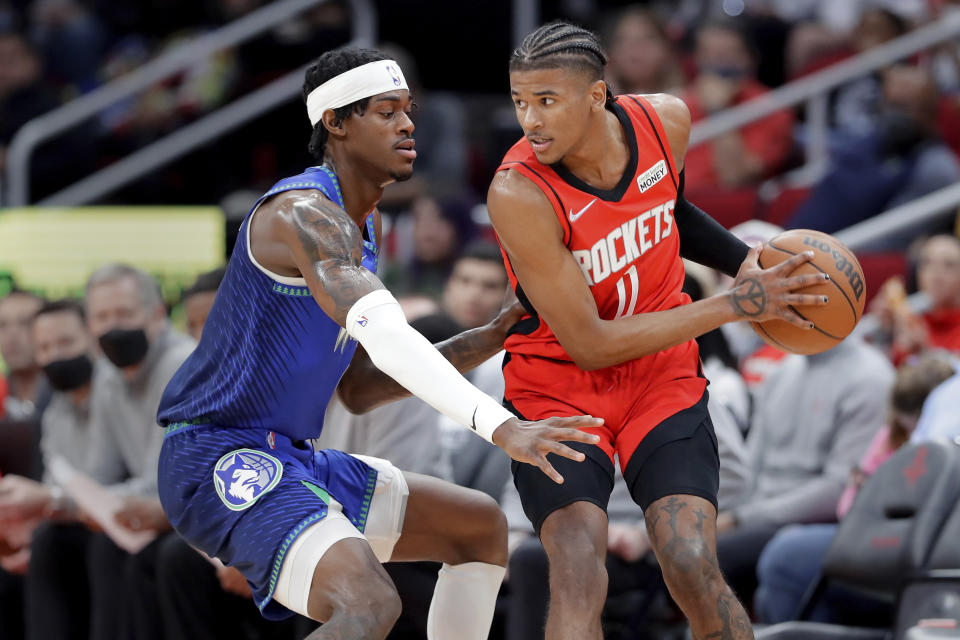 Houston Rockets guard Jalen Green, right, looks to pass the ball under pressure from Minnesota Timberwolves forward Jarred Vanderbilt, left, during the first half of an NBA basketball game Sunday, Jan. 9, 2022, in Houston. (AP Photo/Michael Wyke)