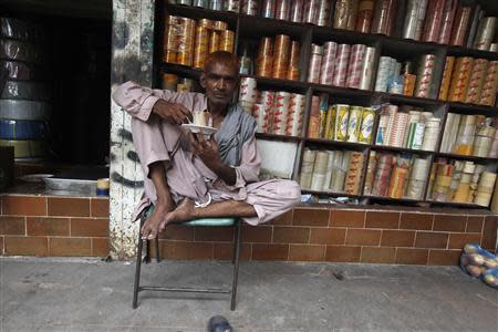 A labourer drinks tea outside a shop in a market in Karachi September 3, 2013. REUTERS/Stringer