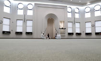 Amid concerns of the spread of COVID-19, a small group prays inside an empty mosque before an Eid al-Fitr celebration in Plano, Texas, Sunday, May 24, 2020. (AP Photo/LM Otero)