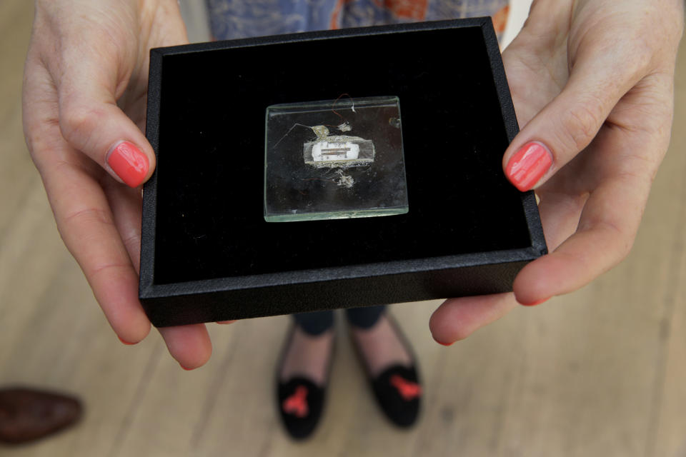 FILE - In this May 23, 2014 file photo, an employee of the Christie's auction house poses for photographs with a 1958 prototype integrated circuit mounted on glass designed by Nobel Prize Physics winner Jack Kilby at Texas Instruments, at premises of the auction house in London, Friday, May 23, 2014.  The prototype microchip, a historical contribution to the modern computing era, is estimated to fetch between $1,000,000 and $2,000,0000 at a June 19 sale in New York.  (AP Photo/Matt Dunham, File)