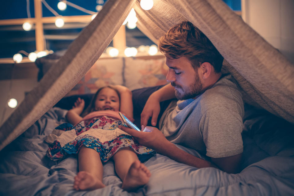 Padre usando el celular junto a su hija. Foto: Svetikd/ Getty Images