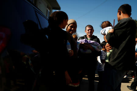 Honduran migrant Alvin Reyes, 39, carries his newborn son Alvin, as he stands next to his wife Erly Marcial, 21, and talks with friends after a religious service at the church where they are staying in Tijuana, Mexico, December 9, 2018. REUTERS/Carlos Garcia Rawlins