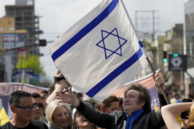 Javier Milei, de la Libertad Avanza, sostiene una bandera israelí durante su caravana por Lomas de Zamora.