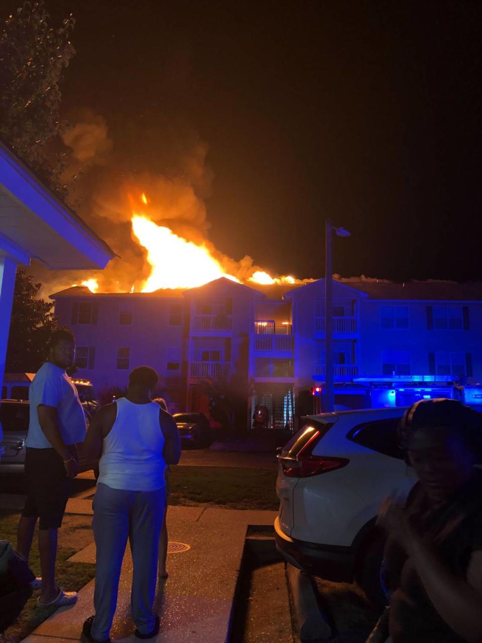 A fire burns through and atop the roof of a building at Providence Pointe apartment complex.