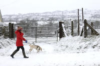 A woman takes her dog for a walk in the snow near Larne, Northern Ireland. (AP)