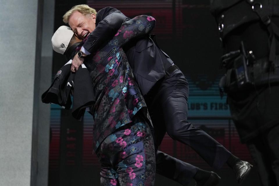 Texas Tech edge rusher Tyree Wilson lifts Roger Goodell into the air with a hug.