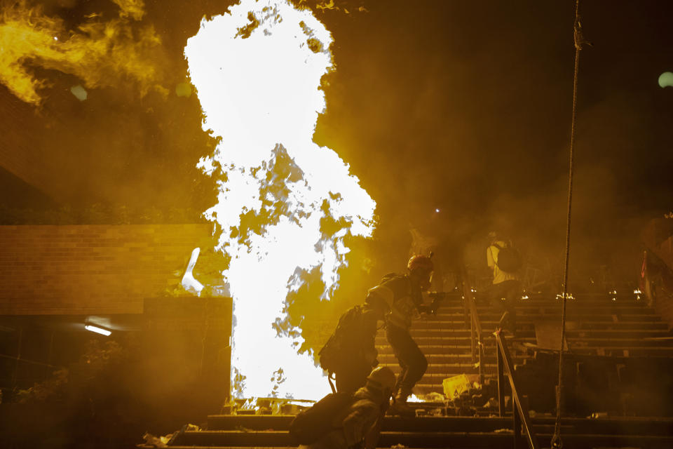 Fires burn as police storm part of the Hong Kong Polytechnic University campus during the early morning hours in Hong Kong, Monday, Nov. 18, 2019. Police breached the university campus held by protesters early Monday after an all-night siege that included firing repeated barrages of tear gas and water cannons. (AP Photo/Ng Han Guan)