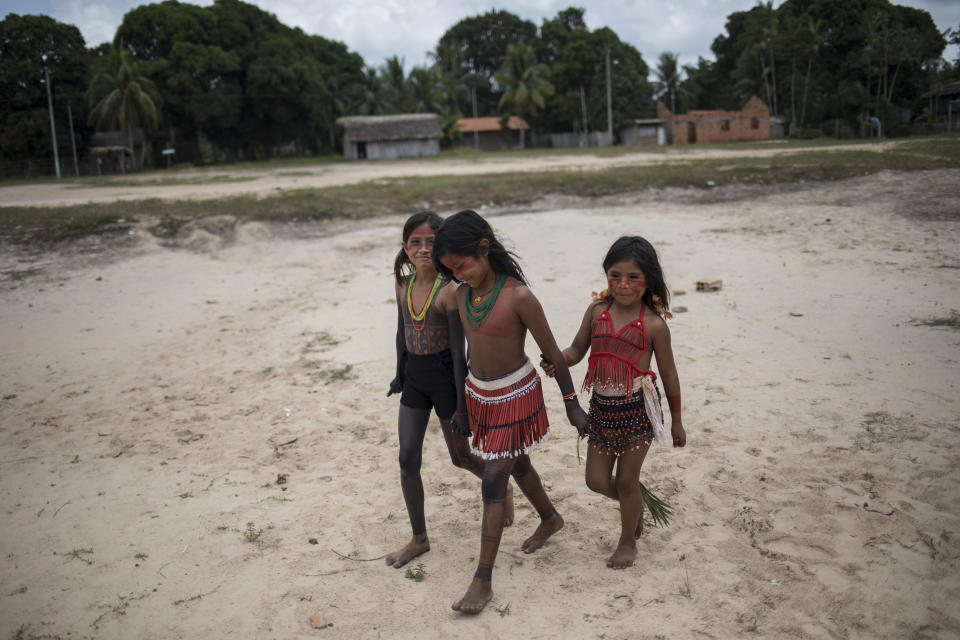 In this Sept. 3, 2019 photo, girls walk towards a meeting of Tembé tribes at the Tekohaw indigenous reserve, Para state, Brazil. Classes had been canceled that day and life in the village seemed to have been put on hold so the Tembé tribes could debate the pros and cons of a plan that some hope will hold at bay the loggers and other invaders threatening the tribes of the Tembé. (AP Photo/Rodrigo Abd)