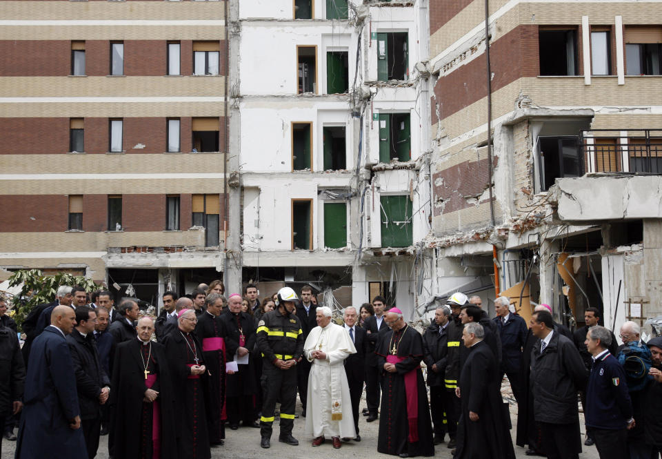 FILE - Pope Benedict XVI, center, talks with a firefighter in front of a collapsed student dormitory following an earthquake in L'Aquila, central Italy, on April 28, 2009. Pope Emeritus Benedict XVI, the German theologian who will be remembered as the first pope in 600 years to resign, has died, the Vatican announced Saturday. He was 95. (AP Photo/Alessandra Tarantino, File)