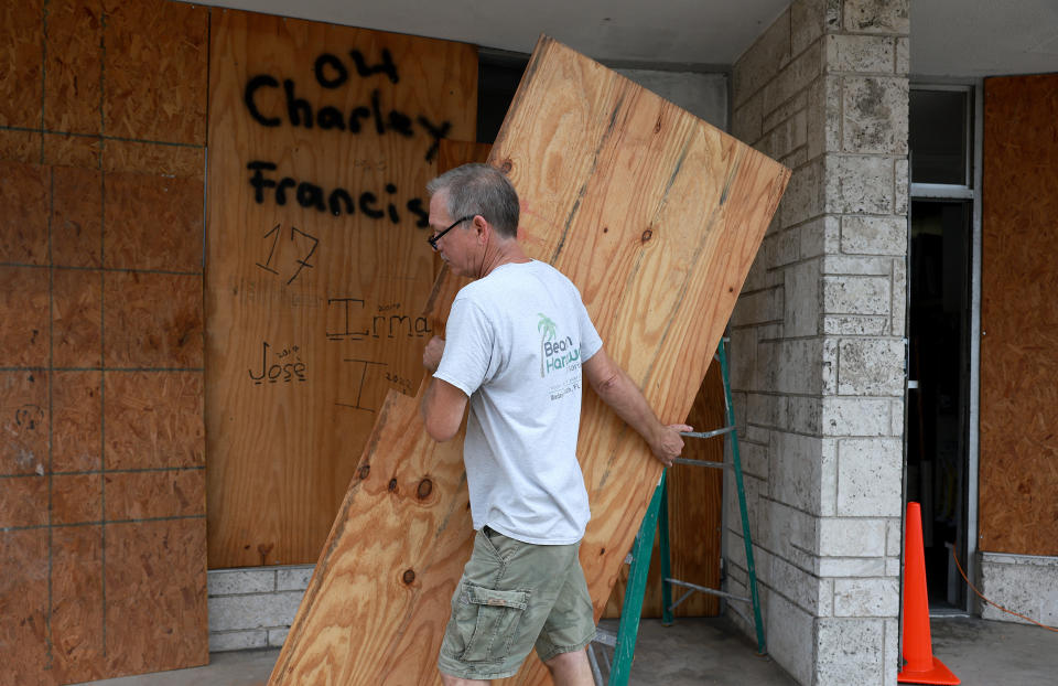 A man boards up his hardware store in advance of Hurricane Ian