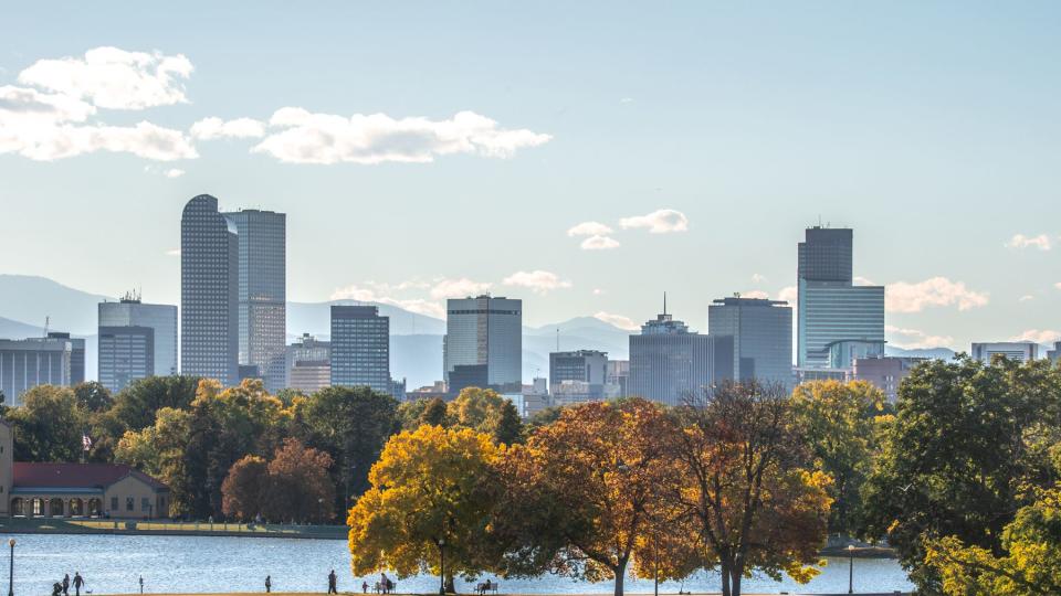 Autumn leaves and lake front with skyline and mountains in the distance in Denver, Colorado.