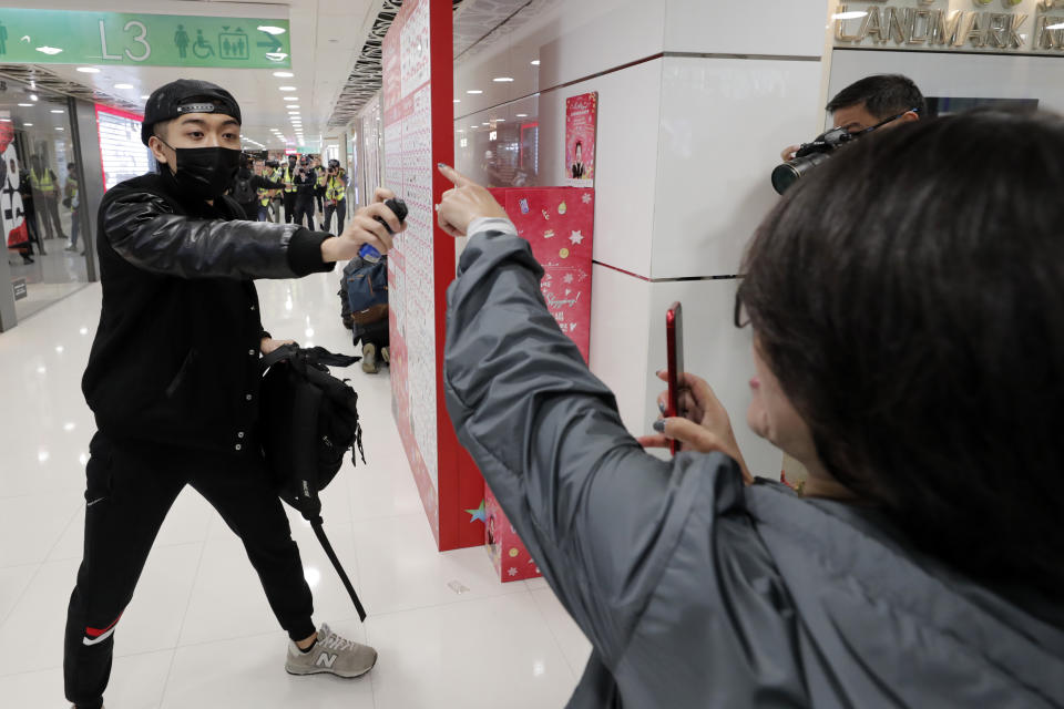 A woman gestures as an undercover policeman points a can of pepper spray during a demonstration at a shopping mall popular with traders from mainland China near the Chinese border in Hong Kong, Saturday, Dec. 28, 2019. Protesters shouting "Liberate Hong Kong!" marched through a shopping mall Saturday to demand that mainland Chinese traders leave the territory in a fresh weekend of anti-government tension. (AP Photo/Lee Jin-man)