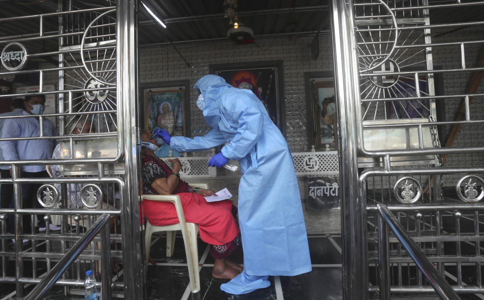 A health worker takes a swab test of a women at a temple in Mumbai, India, Saturday, July 18, 2020. India crossed 1 million coronavirus cases on Friday, third only to the United States and Brazil, prompting concerns about its readiness to confront an inevitable surge that could overwhelm hospitals and test the country's feeble health care system. (AP Photo/Rafiq Maqbool)