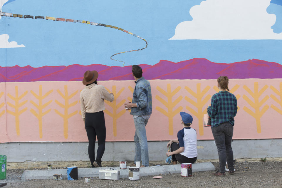 group of people helping to paint a mural