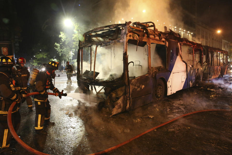 Firefighters put out the flames on a burning bus during a protest against the rising cost of subway and bus fares, in Santiago, Friday, Oct. 18, 2019. (Photo: Esteban Felix/AP)