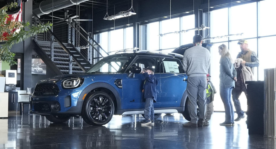 File - Potential buyers look at a 2023 Cooper Countryman S sports-utility vehicle on the floor of a Mini dealership on Friday, Feb. 17, 2023, in Highlands Ranch, Colo. On Friday, the Commerce Department issues its February report on consumer spending. (AP Photo/David Zalubowski, File)