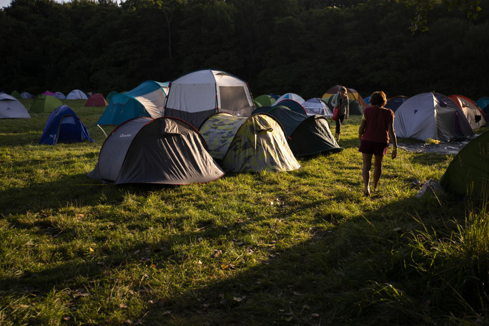 People walk next to tents set up in a camping site Thursday, Aug. 22, 2019, in Urrugne, southwestern France. Various groups of protesters are setting up camps at towns near to the Spanish border, as they prepare for G7 protest actions during the Aug. 24-26 gathering of major world democracies. (AP Photo/Emilio Morenatti)