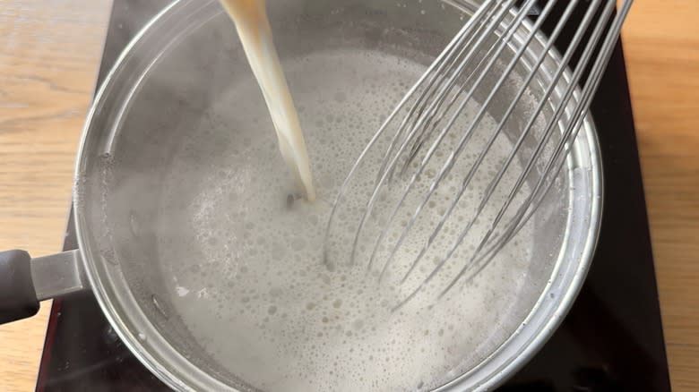 Whisking hot milk into yolks