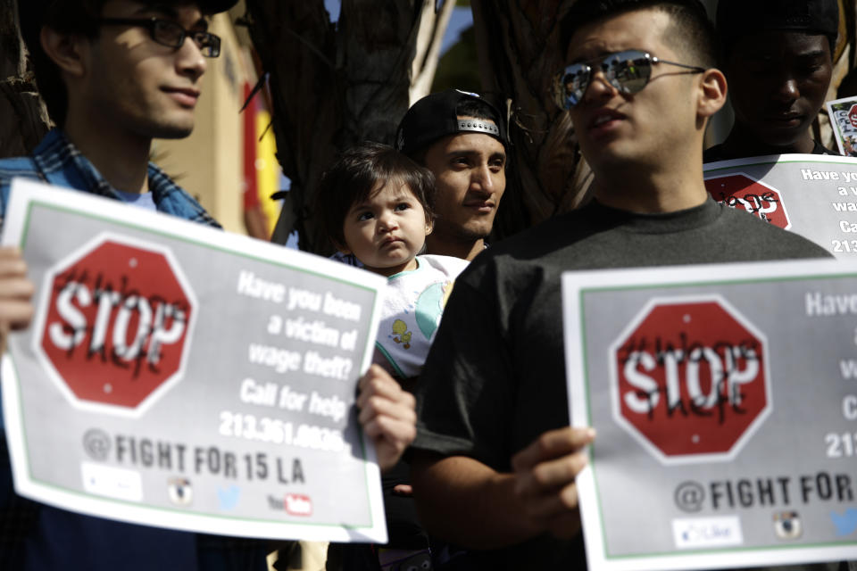 Former fast food worker Angel Santos, center, holds his 1-year-old daughter, Elisa, during a protest outside a McDonald's restaurant on Tuesday, March 18, 2014, in Huntington Park, Calif. Protesters were set to rally outside McDonald's restaurants in cities including Boston, Chicago and Miami to call attention to the denial of overtime pay and other violations they say deprive workers of the money they're owed. (AP Photo/Jae C. Hong)