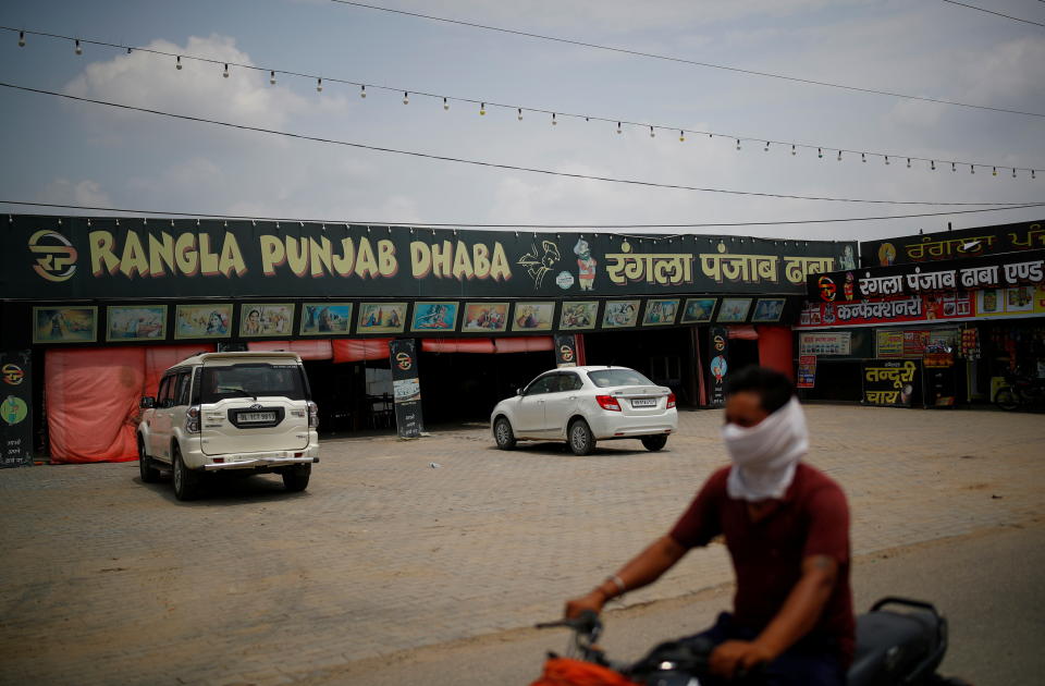 A man rides a motorcycle past a dhaba, a small restaurant along a national highway in Gharaunda