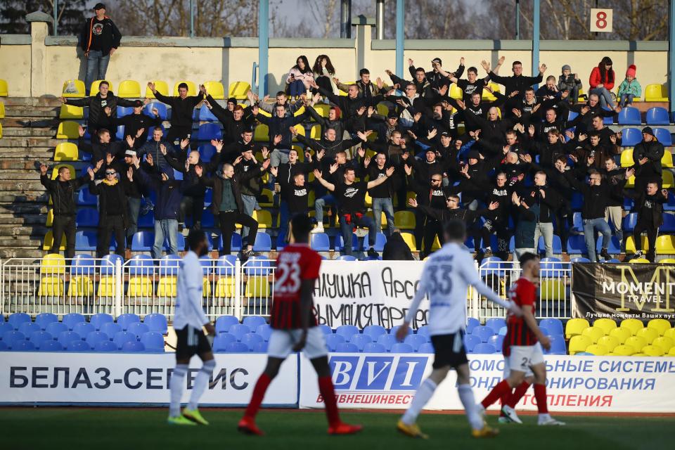 In this photo taken on Friday, March 27, 2020, fans of Torpedo Zhodino cheer during the Belarus Championship soccer match between Torpedo-BelAZ Zhodino and Belshina Bobruisk in the town of Zhodino, Belarus. Longtime Belarus President Alexander Lukashenko is proudly keeping soccer and hockey arenas open even though most sports around the world have shut down because of the coronavirus pandemic. The new coronavirus causes mild or moderate symptoms for most people, but for some, especially older adults and people with existing health problems, it can cause more severe illness or death. (AP Photo/Sergei Grits)