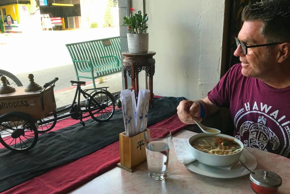 As he digs into his bone-broth chicken soup, visitor and former San Luis Obispo resident David Mott enjoys the view from the window table at Mee Heng Low restaurant on Wednesday, Oct. 25, 2023. The cyclist, who was in town visiting his parents, said he’d learned to love the decades-old Chinese restaurant while attending Cal Poly. Kathe Tanner/ktanner@thetribunenews.com