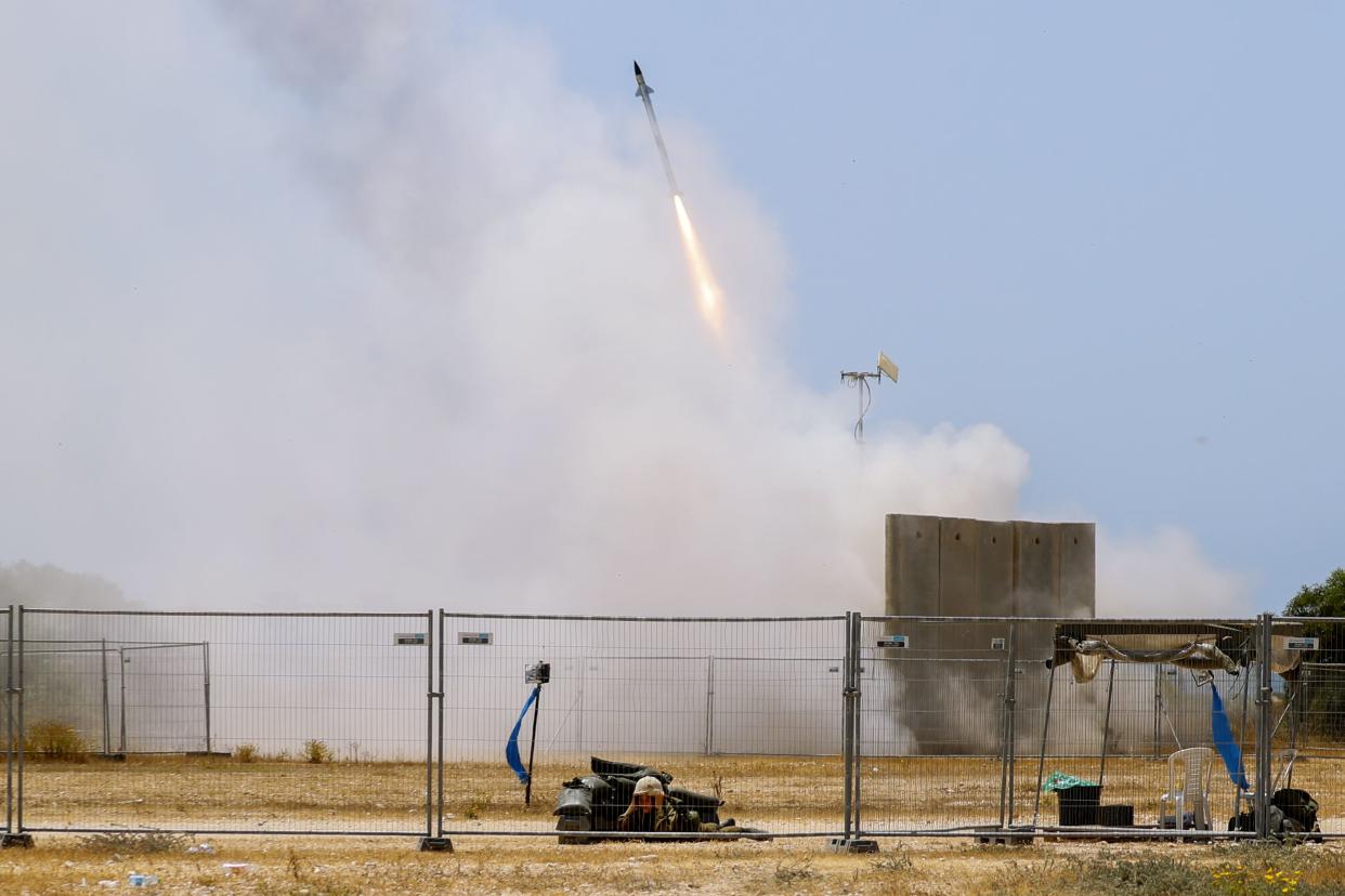 An Israeli soldier takes cover as an Iron Dome air defense system launches to intercept a rocket from the Gaza Strip in Ashkelon, southern Israel, Tuesday, May 11, 2021.