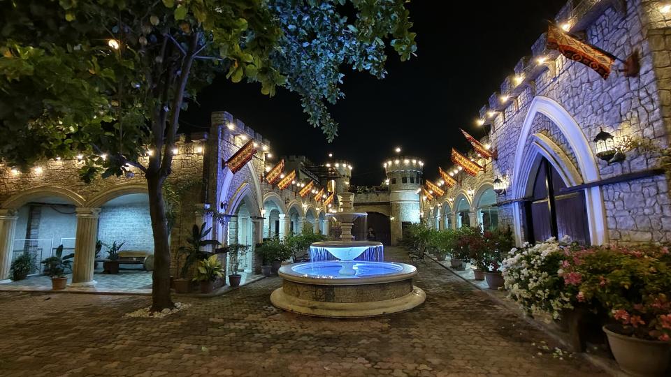 A beautifully lit courtyard with a fountain at night