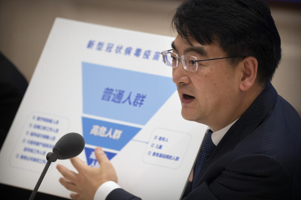 Zheng Zhongwei, an official with China's National Health Commission, holds a chart showing different priority groups for a coronavirus vaccine as he speaks during a press conference held to discuss COVID-19 vaccine-related issues at the State Council Information Office in Beijing, Friday, Sept. 25, 2020. A Chinese health official said Friday that the country's annual production capacity for COVID-19 vaccines will top 1-billion next year, following an aggressive government support program for new factories. (AP Photo/Mark Schiefelbein)