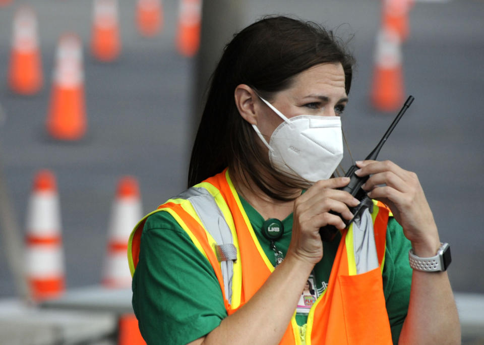 Cathy Fuller, a nurse at the University of Alabama at Birmingham, talks into a handheld radio on Tuesday, May 18, 2021, at a mass COVID-19 immunization site in Hoover, Ala., where declining demand prompted a shutdown. While initially capable of vaccinating as many as 2,400 people daily, site workers said far fewer people have been showing up for shots even though only about 25% of Alabama's population is fully vaccinated. (AP Photo/Jay Reeves)