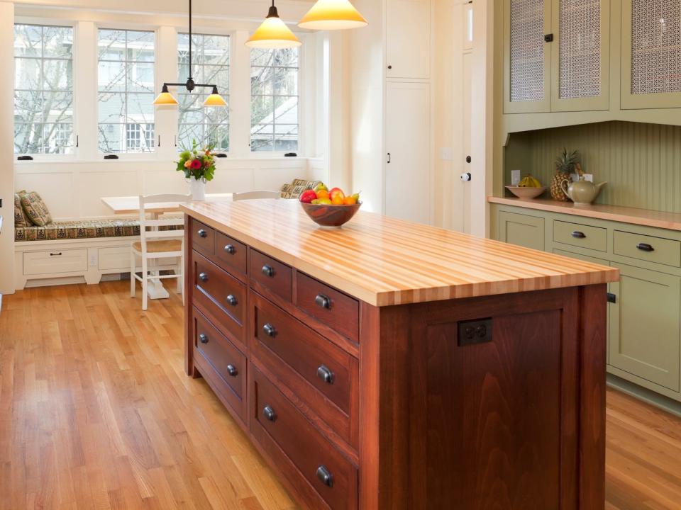 A kitchen with a butcher-block topped center island and black countertops.