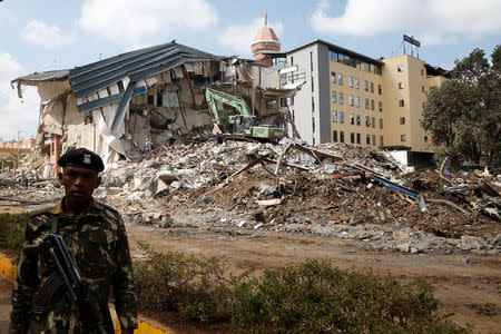 A police officer stands guard as heavy machinery demolishes the UKAY Mall in Westlands, Nairobi, Kenya, August 14, 2018. REUTERS/Baz Ratner